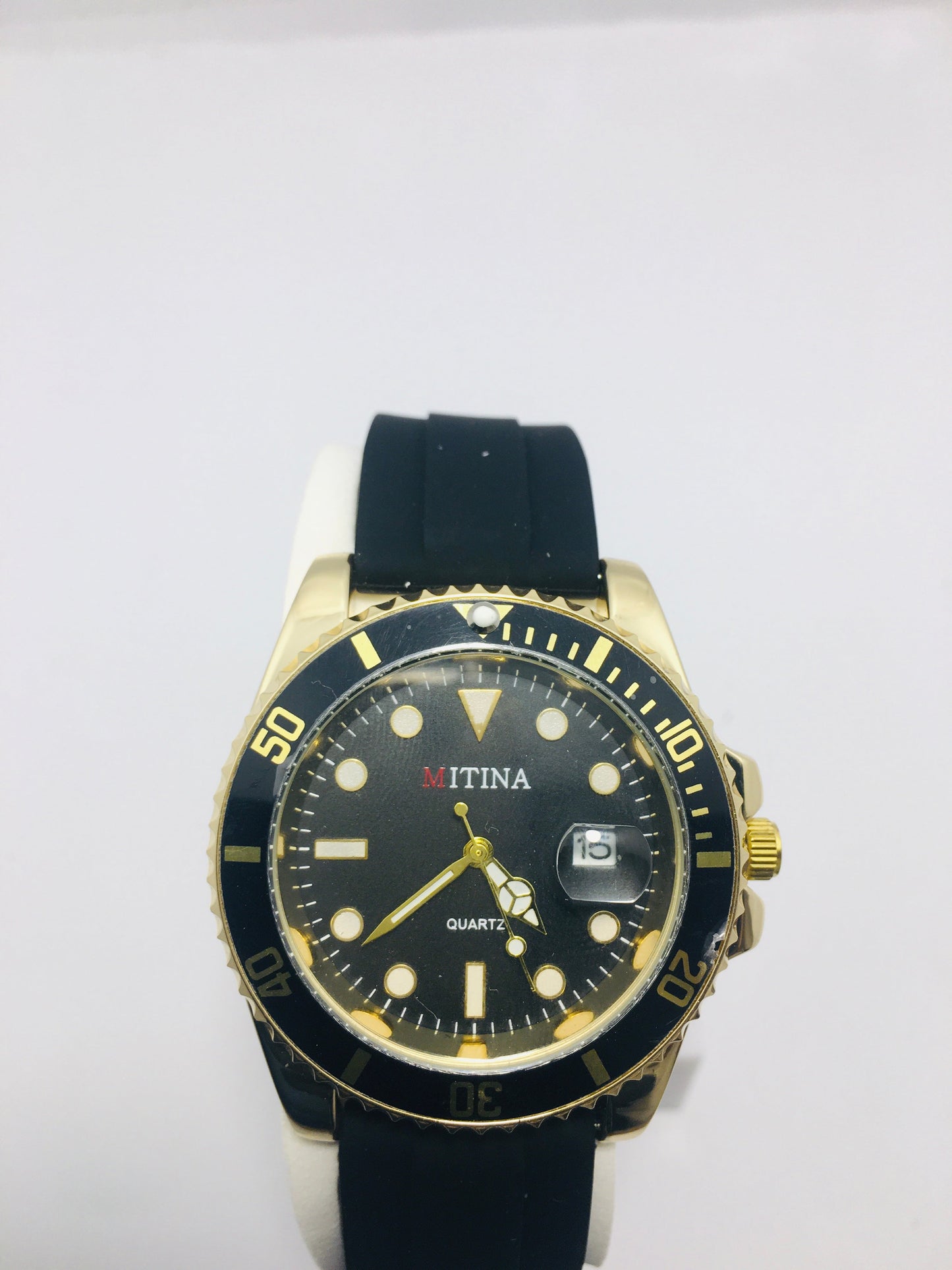 Mitina Movement diver-style watch with a black dial, gold-colored accents, a rotating bezel, and a date window. Rubber strap black